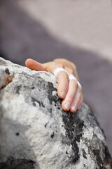 Person, grip and rock climbing or finger tape on hand for exercise injury, sports pain on nature cliff. Athlete, boulder and hanging for explore peak practice for brave adventure, risk on mountain