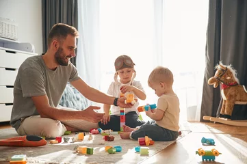 Fotobehang Construction toys. Father is playing with two little boys on the floor © standret