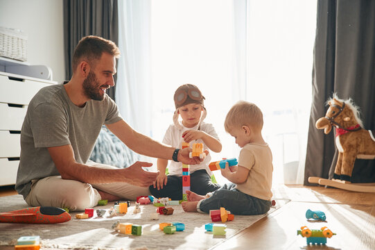 Construction toys. Father is playing with two little boys on the floor