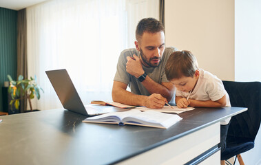 Fototapeta na wymiar Writing the homework. Father and son are at home by the table
