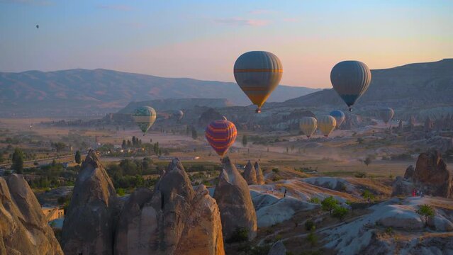 Handheld shot. Captured against the canvas of the Cappadocian sky, this stunning stock photo showcases the enchanting spectacle of a hot air balloon festival. The vibrant balloons rise gracefully over