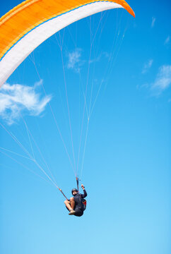 Man, paragliding and blue sky adventure fun in clouds for explore city, outdoor courage or fearless athlete. Male person, parachute and mockup space or safety equipment for landing, flying in nature