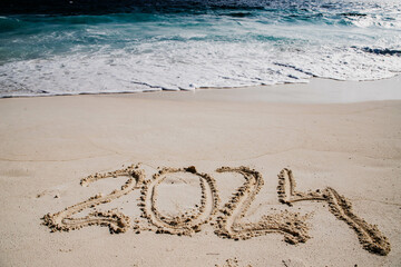 2024 written in white sand on tropical beach, happy New Year