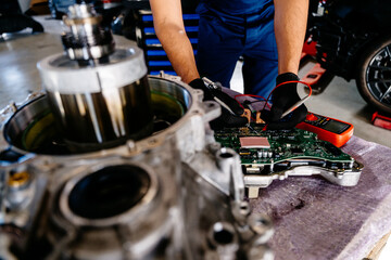 An electric car engine with a gearbox removed from a car for repair. Arabian man working Internal...