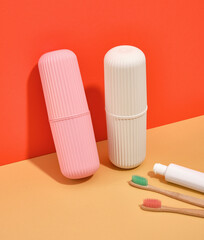 Obraz premium Two plastic cases white and pink colors on table. Organic toothbrushes and toothpaste.