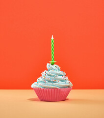 One lovely, gourmet, tasty, yummy dessert cream birthday cupcake with a festive green candle....
