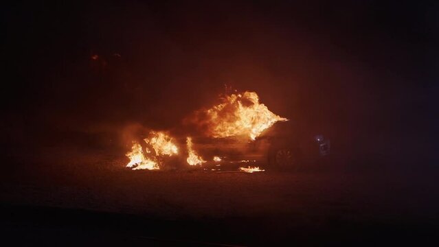Car burning in flames after a car crash at night. High quality 4k footage