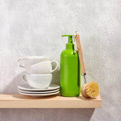 Clean tableware white color. Detergent dispenser in green. Eco wooden dishwashing brush.