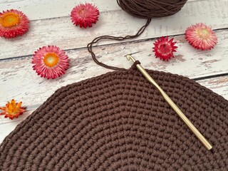 Top view of a crochet project on a wooden table decorated with flowers