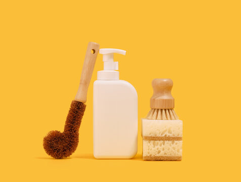 Washing dishes in the kitchen with eco friendly sponges and brushes. White dishwashing gel dispenser.