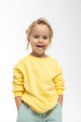 Portrait of beautiful cute little toddler girl. Child with funny face in yellow sweatshirt. Pretty smile kid in studio on white background. High quality photo