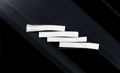 Four white books on a black background. View from above. Copy space.