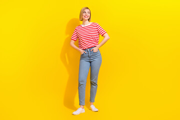 Full size photo of satisfied girl wear stylish t-shirt arms in pockets look at offer empty space isolated on bright yellow background