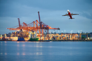 International cargo ship with logistics and containers cargo illumination, gantry cranes and commercial airplane flying at habour - obrazy, fototapety, plakaty