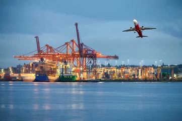 Photo sur Aluminium Canada International cargo ship with logistics and containers cargo illumination, gantry cranes and commercial airplane flying at habour