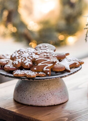 Homemade gingerbread Christmas cookies in icing sugar. Delicious gingerbread cookies on the background of a bokeh of Christmas tree lights. Freshly baked Christmas gingerbread cookies.