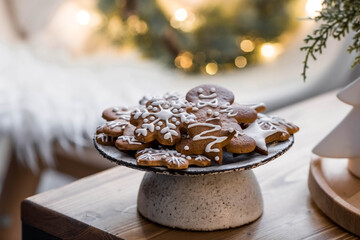 Obraz na płótnie Canvas Homemade gingerbread Christmas cookies in icing sugar. Delicious gingerbread cookies on the background of a bokeh of Christmas tree lights. Freshly baked Christmas gingerbread cookies.