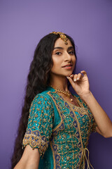 beautiful indian woman in traditional blue sari posing on purple backdrop and looking at camera