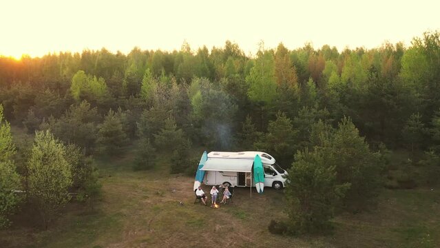 Top view of a family vacation near a campfire next to a mobile home in the woods. The concept of travel