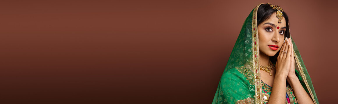 beautiful young indian woman in traditional costume with bindi dot showing praying gesture, banner