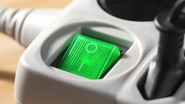 A finger presses the power switch on a surge protector. Close-up, shallow dof.
