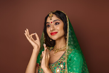 attractive indian woman in national costume with bindi and green veil gesturing and looking away