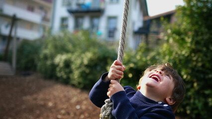 Excited Child in Close-Up, Gripping and Sliding on Wire Rope Between Trees