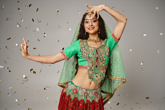 attractive indian female model in traditional clothes posing in motion surrounded by confetti