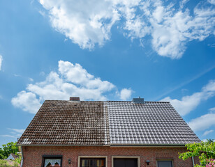A half cleaned house roof shows the before and after effect of a roof cleaning..