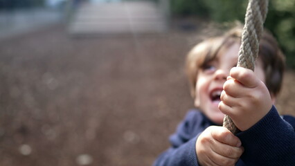 Happy Child Sliding Down Rope at Autumn Playground. Joyful Kid Holding Onto Rope and Enjoying Slide...