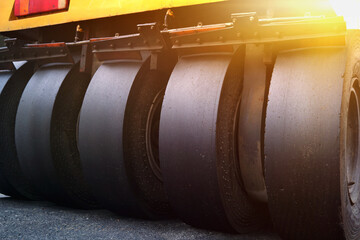 Close-up of large wheels of asphalt paving machines working on the road.