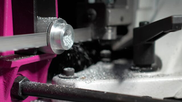close-up image of a CNC (Computer Numerical Control) lathe machining a metal rod, with metal shavings visible around the cutting area. High quality 4k footage