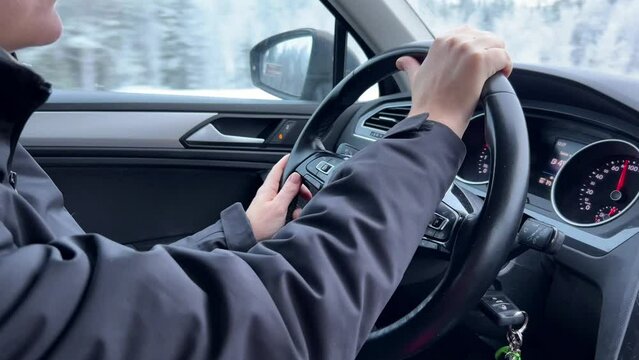 Person driving a car, hands on the steering wheel with dashboard and rearview mirror in view, suggesting focused and attentive driving
