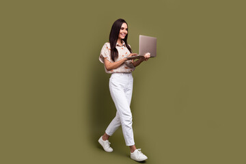Full length photo of attractive mature lady using netbook to communicate with colleagues distantly isolated on khaki color background