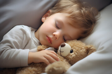 Young boy toddler sleeping next to teddy bear