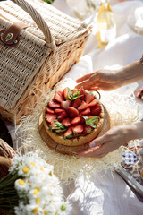 summer picnic with strawberries. Homemade strawberry cake. Open bakery with strawberry cake. The pie stands against the backdrop of a wicker basket surrounded by hay