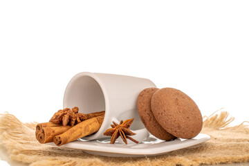 Chocolate, cinnamon, star anise cookies with ceramic cup and saucer on jute napkin, macro, isolated on white background.