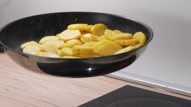 The potato slices are pan-fried by tossing them up.