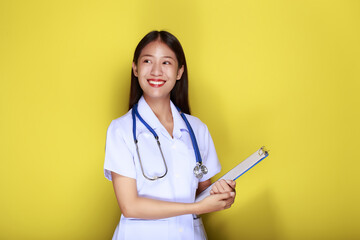 Portrait of a beautiful young woman in a yellow background,  Asian woman wearing a doctor's uniform...