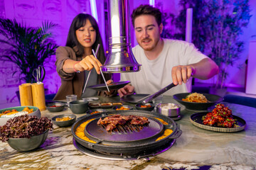 close-up of a couple in love having dinner in a Korean restaurant picking up juicy meat from the...