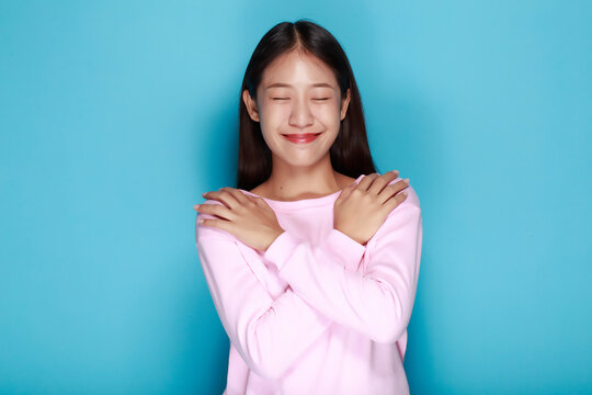 Portrait of a friendly young woman smiling happily, Portrait of a beautiful young woman in a light blue background, half body photo of nice positive lady crossed arms posing empty space ad isolated.