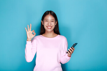 Young woman poses with OK hand while holding a cell phone in the other hand, Portrait of a...