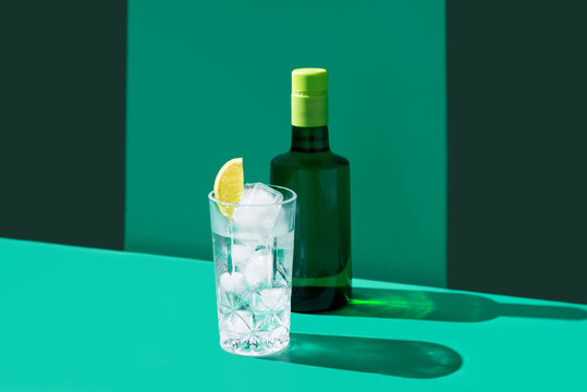 Gin tonic with ice and lime slice on green backdrop