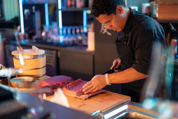 Sushi chef expertly preparing fresh fish at a sushi bar