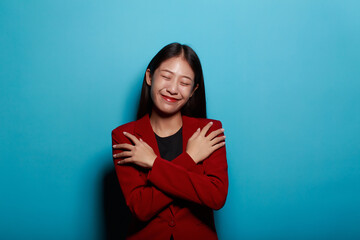 Fototapeta premium Portrait of a friendly young woman smiling happily, Portrait of a beautiful young woman in a light blue background, half body photo of nice positive lady crossed arms posing empty space ad isolated.