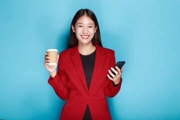 A woman has a blue background as a backdrop for a single portrait, smiling and holding a cell phone...