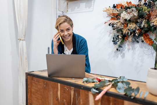 Florist taking order over phone with laptop at counter