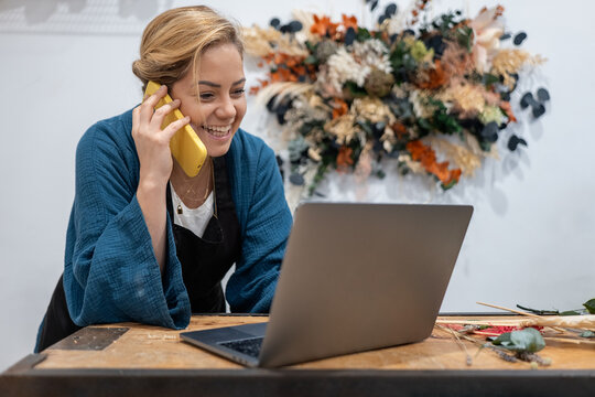 Florist taking order over phone with laptop at counter