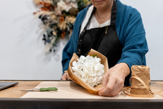 Anonymous person crafting a bouquet with white flowers and paper