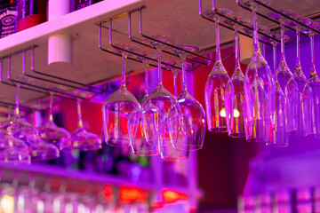 glass glasses on bar counter in neon pink light in restaurant or bar celebration alcoholic drinks